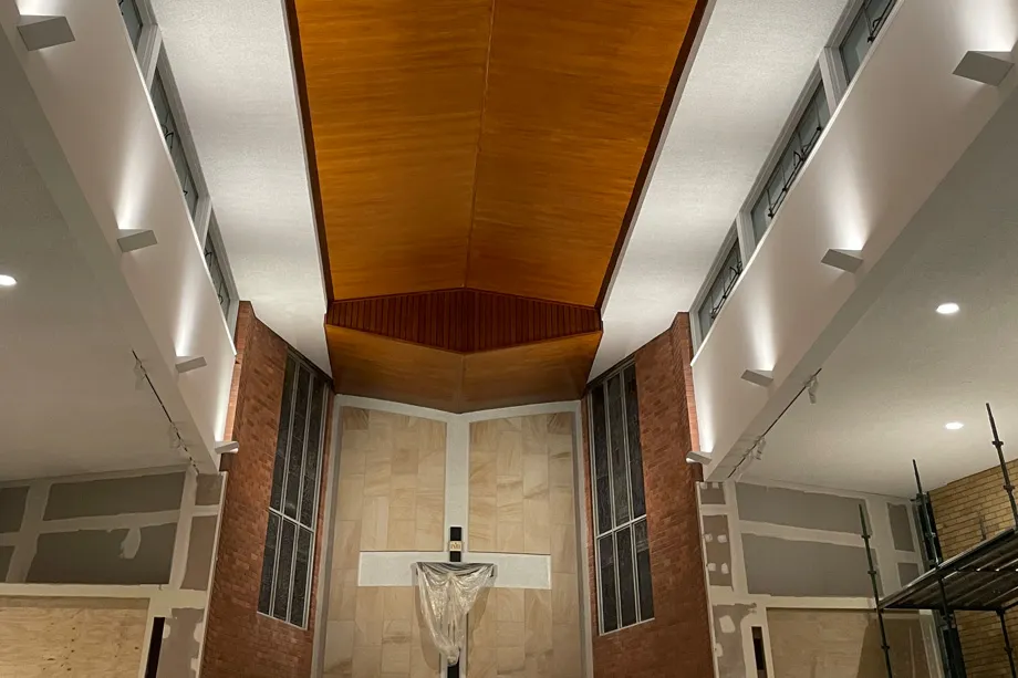 Church sanctuary with freshly painted white upper walls, a timber-lined ceiling and face-brick piers