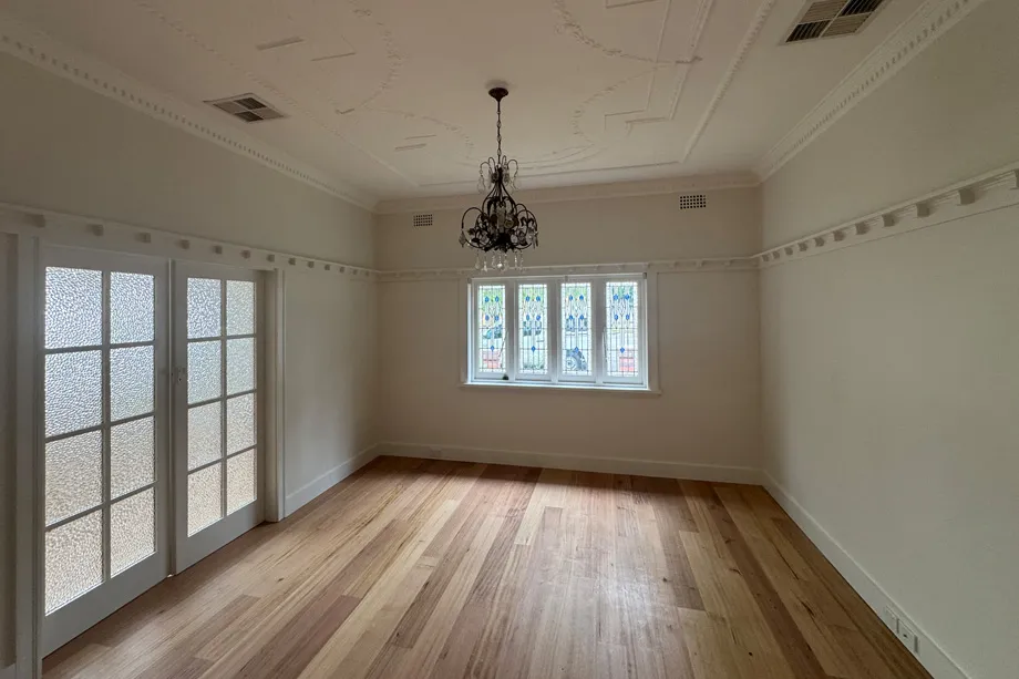 Federation room with cream walls, a white picture rail, an ornate ceiling, a chandelier and glazed French doors