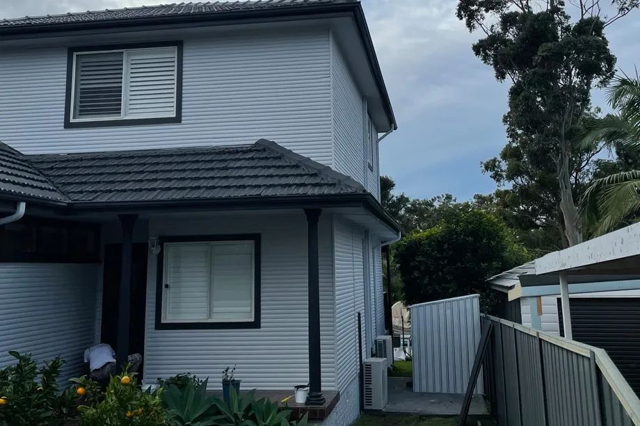Two-storey light grey weatherboard house with charcoal trims and a tiled roof